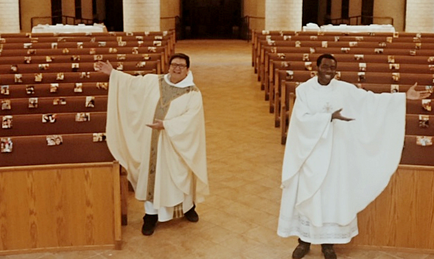 Father Jaime Acevedo, left, and Father Paul Karenga show the photos taped by parishioners to the pews at St. Mark Church, to show their support even if they couldn't attend physically.