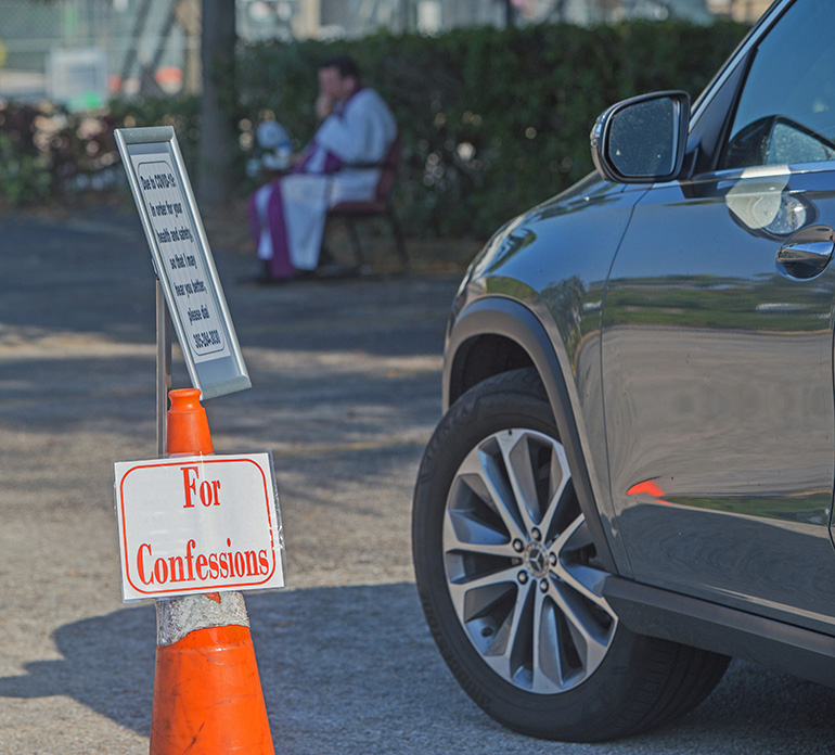 El P. Richard Vigoa escucha confesiones en el estacionamiento de la iglesia de St. Augustine el 26 de marzo de 2020. Un día después, una directiva de la Santa Sede prohibió el uso de teléfonos celulares debido a la preocupación por las lagunas de seguridad o las escuchas electrónicas que entrarían en conflicto con la "absoluta inviolabilidad del sello confesional". Unos días después, el 1 de abril, el arzobispo Thomas Wenski pidió a las parroquias que suspendieran todas las operaciones de "drive-through" y cualquier otra cosa "que animara a la gente a dejar sus casas", para minimizar los riesgos de contagio.