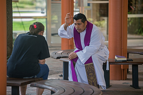 Father Antonio Tupiza hears a confession in the kiosk area of St. Rose of Lima Church, Miami Shores, March 28, 2020. Priests in the archdiocese continue to hear confessions by appointment while following social distancing measures to protect themselves and parishioners against COVID-19.