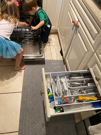 Angela Amaro, 5, and Jorge, 2, empty the dishwasher and store the utensils in the drawer.