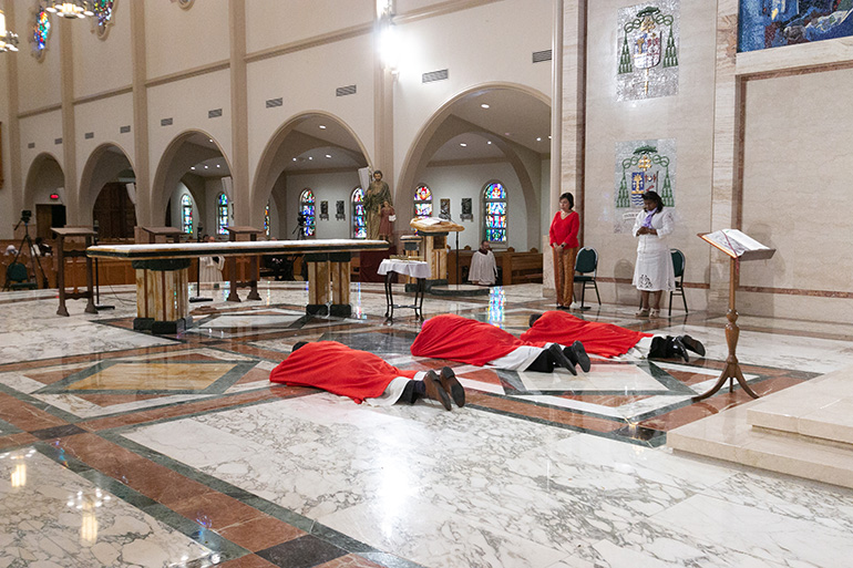 Archbishop Thomas Wenski, center, accompanied by two deacons, lies prostrate on the sanctuary of St. Mary Cathedral in Miami at the start of the Good Friday liturgy of the Passion of the Lord, April 10, 2020. Due to the coronavirus pandemic, only Missionaries of Charity and a few cathedral staff were present. The Mass was livestreamed on the Archdiocese of Miami's Facebook and YouTube pages.