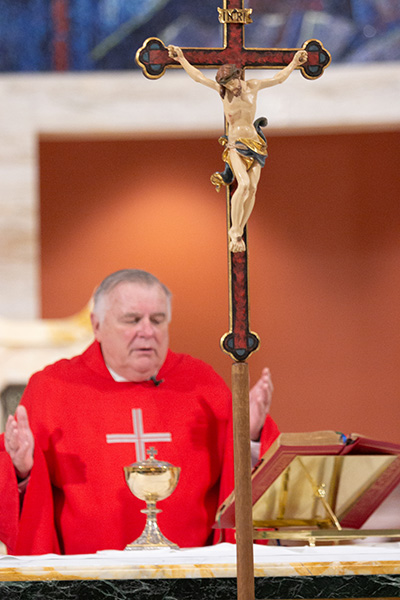 Archbishop Thomas Wenski prays the Our Father before distributing Communion during the Good Friday liturgy of the Passion of the Lord celebrated in a nearly empty St. Mary Cathedral, April 10, 2020.