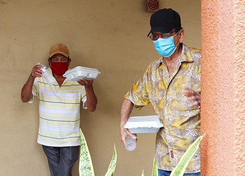 Residents of an apartment building in Little Haiti, wearing masks to protect against COVID-19, are grateful to receive their hot meals prepared and delivered by volunteers of Notre Dame d'Haiti Mission on April 11, 2020.