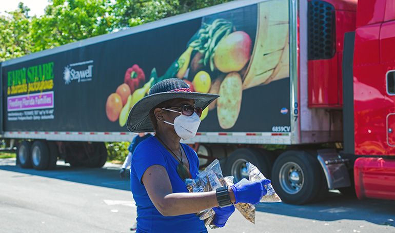 A volunteer carries walnuts to a car during the food distribution hosted by Notre Dame d'Haiti Church in Miami April 23, 2020. The food, donated by Farm Share, helped residents of Little Haiti, many of whom have lost their jobs due to the coronavirus pandemic.