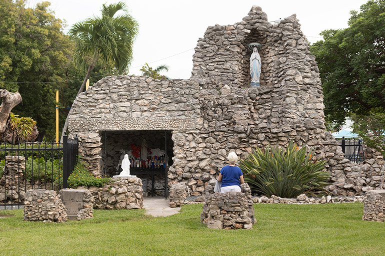 A woman takes time for prayer at the historic grotto to Our Lady at the Basilica of St. Mary Star of the Sea in Key West. The minor basilica is one of the oldest Catholic parishes in the state of Florida and the oldest parish in the Archdiocese of Miami. Father John Baker, rector of the basilica, said people continue to come to the outdoor shrine to pray during this coronavirus pandemic.