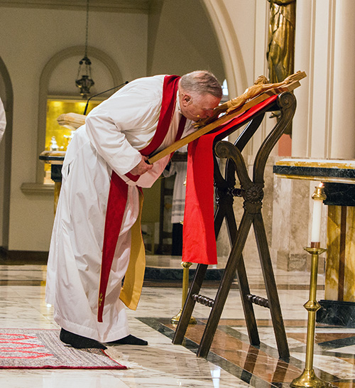 Archbishop Thomas Wenski venerates the cross during the Good Friday Service of the Lord's Passion at St. Mary Cathedral in this file photo from 2017. Vatican guidelines this year state: "The adoration of the cross by kissing it shall be limited solely to the celebrant." And of course, the liturgy will take place without a congregation although it, and all the Triduum liturgies, will be livestreamed on the archdiocese's Facebook and YouTube pages.