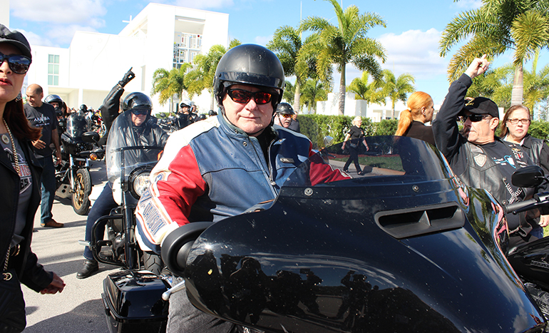 With Doral's Our Lady of Guadalupe Church in the background, Archbishop Thomas Wenski prepares to take off for Peterson's Harley Davidson during his annual Motorcycle Ride to raise funds for St. Luke's Center, Feb. 23, 2020.