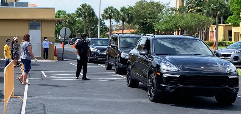 Father George Packuvettithara, St. Rose of Lima's pastor, wears a mask and keeps his distance as cars drive by to drop off food donations April 29, 2020. School families and parish volunteers restocked neighboring St. Martha Parish's Food Pantry thanks to donations of nonperishable foods from their fellow parishioners.