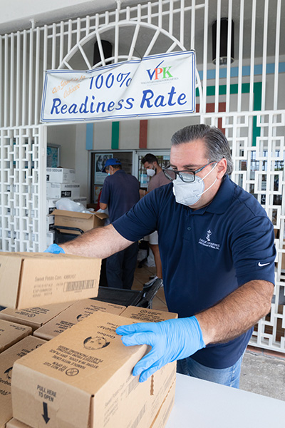 Keith López, gerente de instalaciones en el Centro Hispano Católico de Miami, ayuda a servir a unos 150 vehículos, representando casi
200 hogares, que asistieron a la distribución de alimentos de Caridades Católicas de la Arquidiócesis el 30 de abril de 2020.