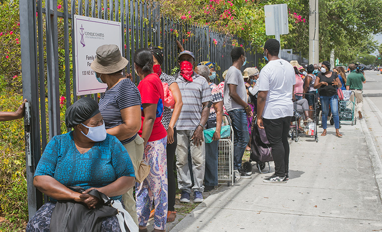 People line up outside Notre Dame d'Haiti Church in Little Haiti to receive donated food. Archbishop Thomas Wenski helped Father Reginald Jean-Mary, Notre Dame d'Haiti's pastor, hand out food at the church May 23, 2020.