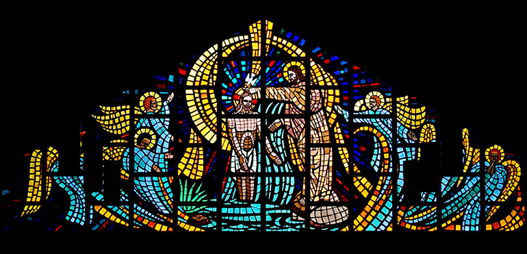 Angels joyfully whip up the Jordan River as Jesus is baptized, in a window that fills the east gable at St. John the Baptist Church.