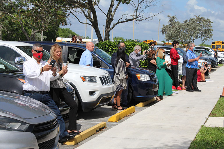 With COVID-19 safety measures in effect, parents, families and friends of Archbishop Coleman Carroll High graduates were requested to wait by their cars, or behind the school's sidewalk, as they watched the commencement ceremony May 30, 2020.