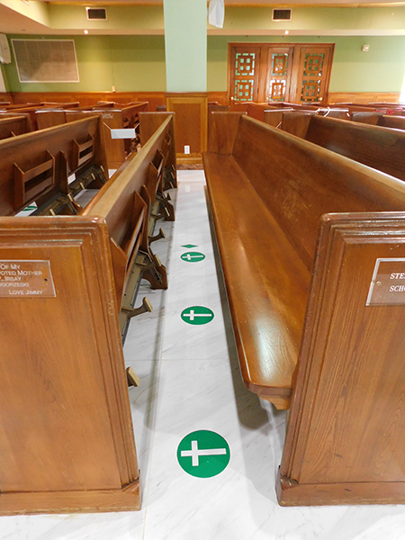 At St. Joseph Church, Miami Beach, green crosses on the floor indicate the places in the pews where people are allowed to sit, in keeping with the norms established for the re-opening of churches.