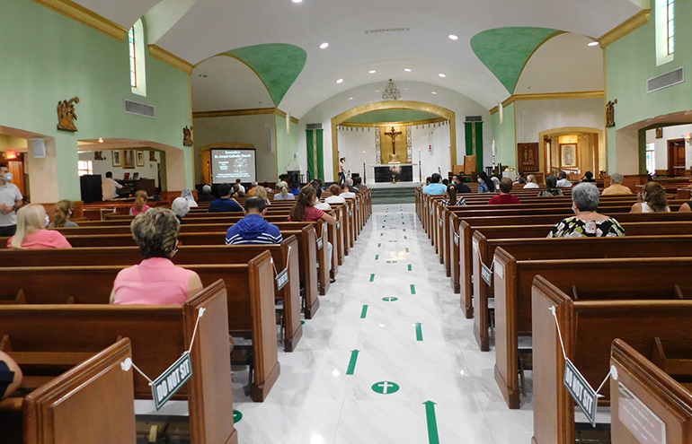 La señalización en el piso establece la distancia de seis pies que debe ser respetada mientras se espera para recibir la comunión, en la parroquia St. Joseph, en Miami Beach.