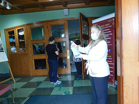 Gipsy Lodos, whose task is to shape the "new normal" at St. Joseph Church, Miami Beach, welcomes the faithful to Mass June 7, 2020, by making sure they sanitize their hands.