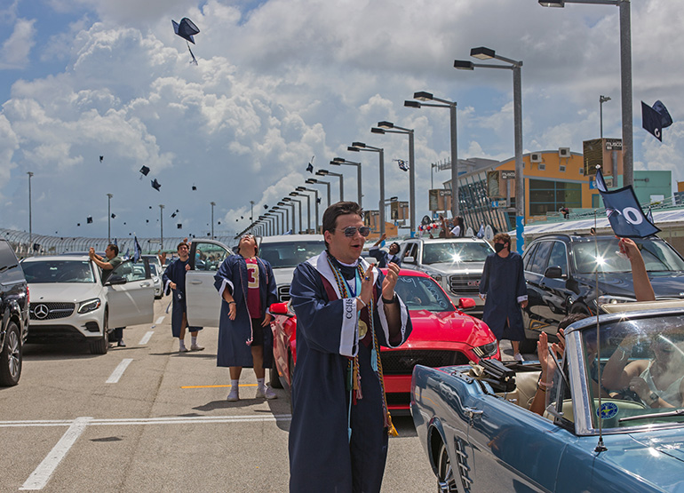 Christopher Columbus High School graduate Marcel Van Hemert applauds as classmates toss their caps into the air at the end of the ceremony. Because of the pandemic, the Miami school celebrated its graduation at the Homestead Miami Speedway June 20, 2020.