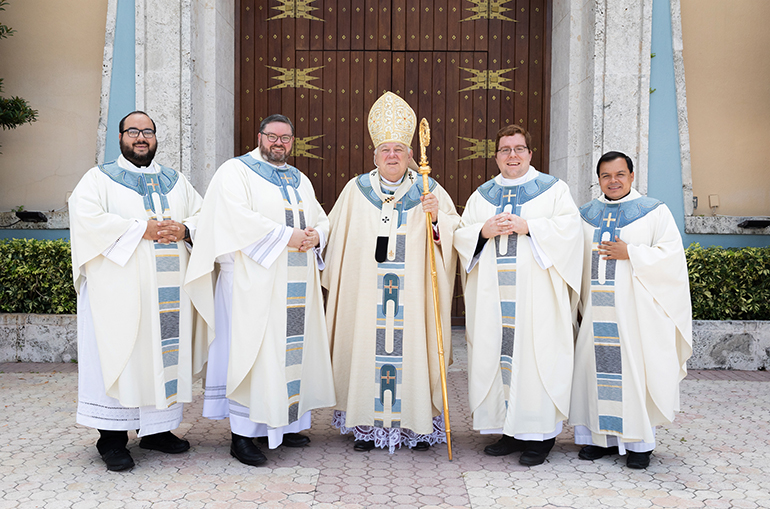 Newly ordained Father Ryan Saunders, center left, and Father Andrew Tomonto, center right, pose for a photo with Archbishop Thomas Wenski, center, and the outgoing and incoming archdiocesan vocations directors, respectively Father Elvis Gonzalez, far right, and Father Matthew Gomez, far left.
Archbishop Thomas Wenski ordained two South Florida natives to the priesthood for the Archdiocese of Miami June 27, 2020. The ceremony had been postponed from May due to the COVID-19 outbreak, and was still punctuated by mask-wearing and social distancing among the limited number of both faithful and priests in attendance.
