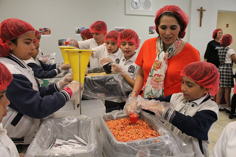 In this file photo from 2017, Our Lady of Lourdes School's third-grade teacher, Ana-Yvette De Atienza, supervises her students as they prepare meal bags for the hungry in Burkina Faso, Africa. The Supreme Court ruled July 8, 2020 that "that educating young people in their faith, inculcating its teachings, and training them to live their faith are responsibilities that lie at the very core of the mission of a private religious school."