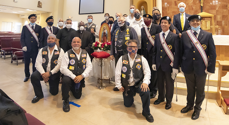 Archbishop Thomas Wenski stands next to the statue of Our Lady of Guadalupe with the Silver Rose icon, after a special prayer service July 3, 2020 at St. John XXIII Church in Miramar, marking the visit of the Silver Rose Pilgrimage through the Archdiocese of Miami. Members of the Knights of Columbus Council 14390 and members of the Knights on Bikes are gathered around the archbishop.