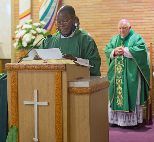 Spiritan Father Alexander Ekechukwu, Holy Redeemer's pastor, greets the congregation at the start of the Mass for unity against racism and for peace, July 5, 2020. Archbishop Thomas Wesnki, standing behind him, presided.