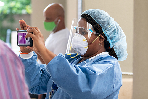 A healthcare worker at Camillus House shelter for the homeless in Miami documents the July 23, 2020 visit of Dr. Jerome Adams, the 20th U.S. surgeon general. He visited Miami to tour the shelter and lead conversation with community leaders about the COVID-19 pandemic.