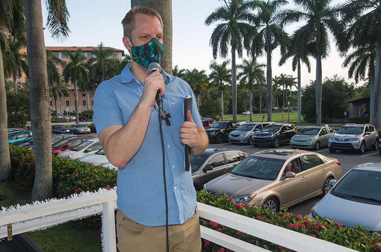 Aaron Lauer, associate pastor at Coral Gables Congregational Church, speaks to participants at PACT's drive-in rally July 27, 2020.  Cars filled the parking lot of Coral Gables Congregational and a vacant lot nearby to listen to PACT speakers who urged more funds for affordable housing and a community ID.