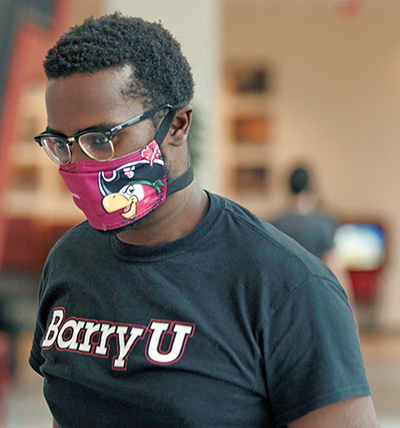 A student models the face mask, branded with Bucky the Barry University mascot, that the university will give everyone who works and studies there.