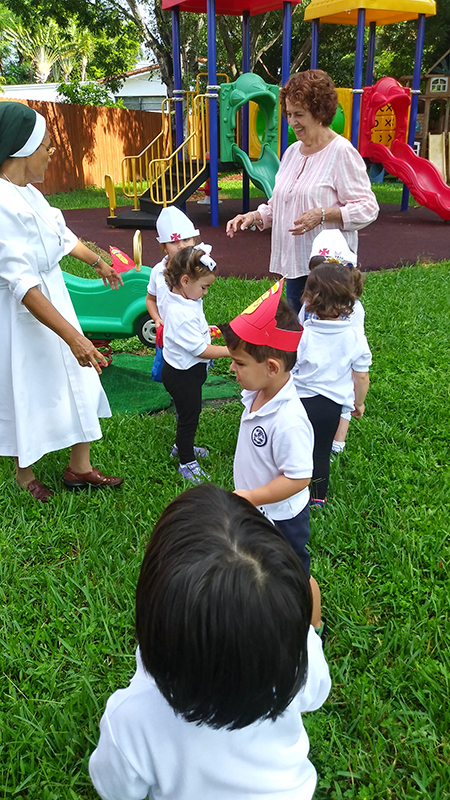 Children enrolled at the Theatine Sisters Day Care in Miami play in the central courtyard; with them are Sister Maria Dolores Moya, left, and Barbara Arias, a lay Theatine who helps care for the children. Currently, due to the coronavirus pandemic, all activities that require direct physical contact with the children have been suspended.