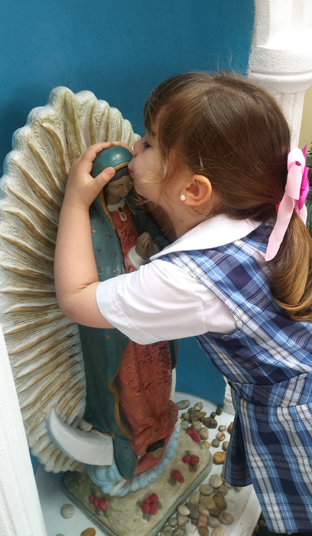 A preschooler who attends the Theatine Sisters Day Care in Miami kisses an image of Our Lady of Guadalupe.