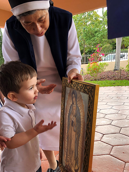 Sister María del Rosario Gutiérrez, director of the Theatine Sisters Day Care, shows an image of Our Lady of Guadalupe to a preschooler enrolled at the center.