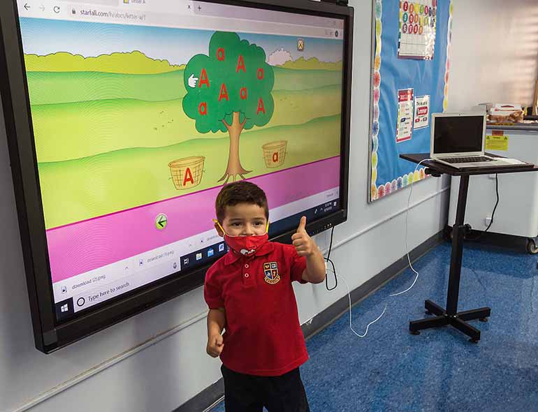 St. Hugh pre-K student Andres Valverde, 3, gives a thumbs up to smart board on the first day of school, Aug. 19, 2020. Pre-K students returned in person while K-12 students did so virtually due to the COVID-19 pandemic.