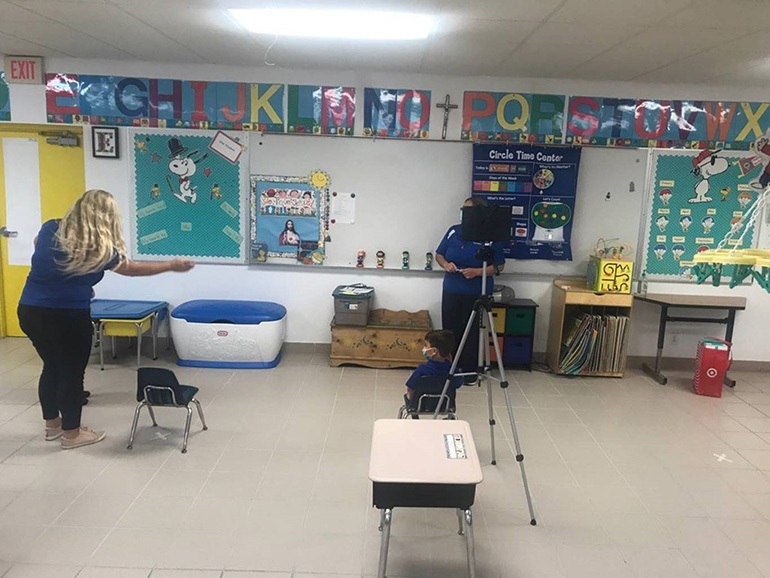 Our Lady of Lourdes School's PreK3 teacher, Nora Estrada, sets up circle time for in person instruction on the first day of school, Aug. 19, 2020. At right, an iPad is on the tripod for the virtual students.. PreK parents could choose between in-person and online instruction.