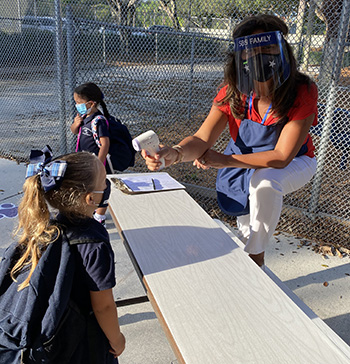 St. Bonaventure's Alicia Dominguez checks a PreK4 student's temperature on the first day of the 2020-2021 school year, Aug. 19, 2020. PreK students