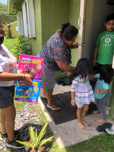 Voluntarios del Centro Educativo La Salle entregan pañales a las familias con niños pequeños que viven en Campamento de Trabajadores Agrícolas de South Dade. Muchos de los pañales fueron donados por la escuela jesuita de Belén.