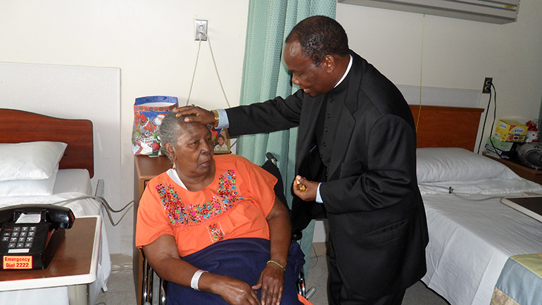 Father Parker Ogboe blesses a resident at Villa Maria Nursing Center in North Miami in this Catholic Health Services file photo from 2009. Pope Francis gave Father Ogboe the title of monsignor in August 2020.