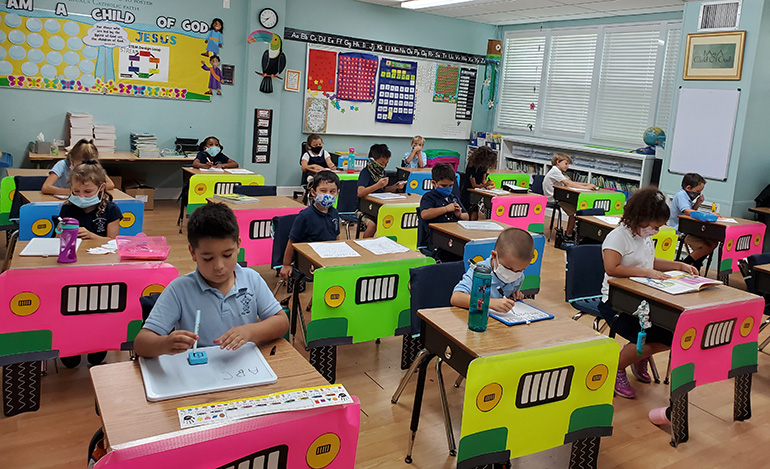 First grade students at The Basilica School of St. Mary Star of the Sea work in their classroom. The students take short breaks from time to time from wearing their mask, but then put the mask back on. Their teacher, Kyle Farrell, explained that the 6-year-old boys and girls "are very good" about wearing their facial coverings as part of the new normal.