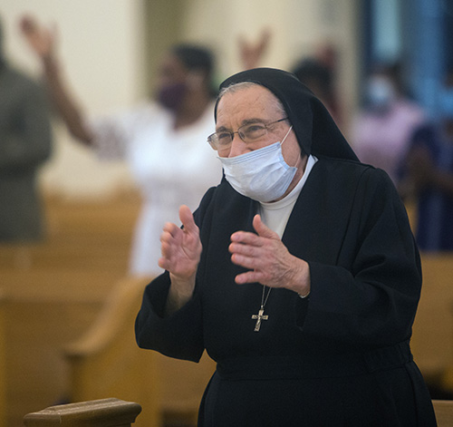 Salesian Sister Yamile Saieh claps along to the lively music of "Alleluia, Amen!" which the church choir sang before the Gospel reading at her farewell Mass at Notre Dame d'Haiti Church in Miami, Sept. 15, 2020.