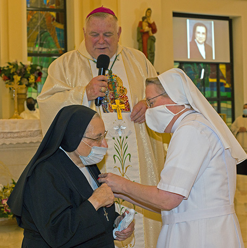 Salesian Sister Suzanne Dauwalter, right, pins the Primum Regnum Dei medal - the highest honor bestowed by the archdiocese - on fellow Salesian Sister Yamile Saieh as Archbishop Thomas Wenski looks on at the conclusion of her farewell Mass, celebrated at Notre Dame d'Haiti Church in Miami, Sept. 15, 2020.