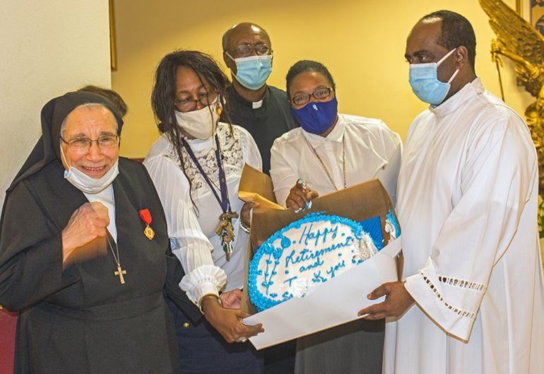 Salesian Sister Yamile Saieh is presented with her retirement cake by Father Reginald Jean-Mary, Notre Dame d'Haiti's pastor, far right; Maggie Sanon, church secretary, second from left, and Sister Sylvana Calixte as Father Lesly Jean looks on. Archbishop Thomas Wenski celebrated a farewell Mass at Notre Dame d'Haiti Church for retiring Salesian Sister Yamile Saieh, Sept. 15, 2020.