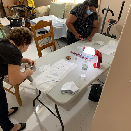 Two members of the Secular Franciscan Order Espejo de Cristo Luisa Ortega, OFS, (left) and Margien Espinosa, OFS, cut patterns to make masks.