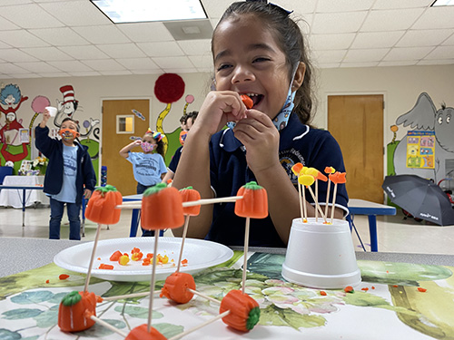 Mother of Our Redeemer PreK-3 student, Nicole Ayala, can't resist tasting some of her work on the Candy Corn Challenge.