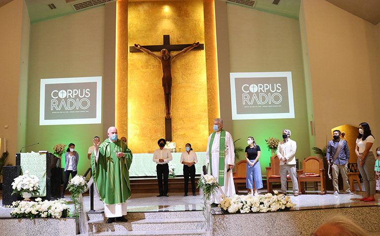 El P. Federico Capdepón (izquierda), director general de Corpus Radio, la nueva emisora radial de la parroquia Corpus Christi, en Miami, presenta durante la Misa de inauguración a los jóvenes que ayudaron en este proyecto. Escucha con ellos el P. José Luis Menéndez, párroco de Corpus Christi.