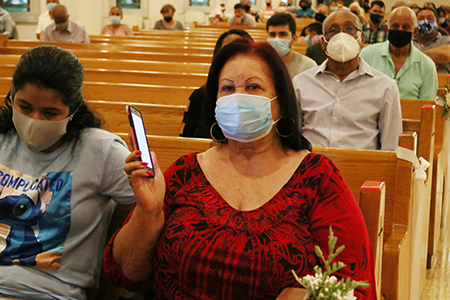 Virginia Salas, a Corpus Christi parishioner for over 30 years, takes out her smartphone to download the Corpus Radio app with the help of her granddaughter, Samanta Reyes, on October 4, during the launching Mass of the new community radio station.