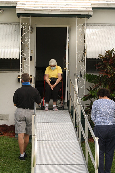 An appreciative Carol Ann Borum bows her head and prays the first decade of the Joyful Mysteries with the Caravan for Christ participants who visited her home July 25, 2020. Praying with her are Blessed Trinity parishioner Paul Zilio, left, who spearheaded the weekly event, and fellow parishioner Alina Rouch.