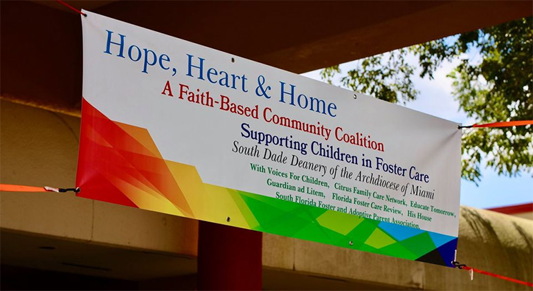 Hope, Heart & Home ministry's banner hangs at the entrance to St. John Neumann Church in Miami during the backpack giveaway in August.