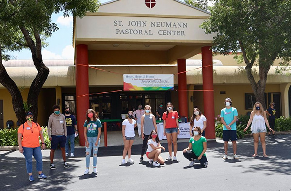 Young adult volunteers are ready to help Hope, Heart & Home load backpacks into cars at the ministry's August giveaway at St. John Neumann Parish in Miami.