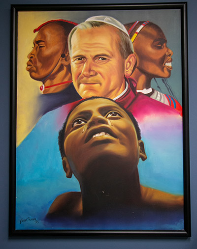 Esta pintura, que conmemora las visitas de San Juan Pablo II a África, cuelga en la pared de la oficina de Katrenia Reeves-Jackman, directora de la Oficina arquidiocesana del Ministerio Católico Negro.