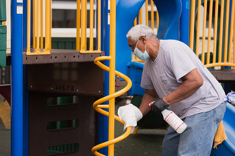 A staff person cleans playground equipment at the Head Start and Early Head Start program at Holy Redeemer Church in Miami, one of six such programs throughout Miami-Dade County operating at reduced in-class capacity during the COVID-19 global pandemic.