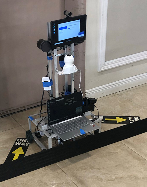 Un robot de telepresencia construido y controlado por Julianne Rodríguez espera en el ascensor dentro de la Comunidad de Vida Asistida Pointe. El robot se dirigirá a las habitaciones de los residentes para que puedan tener una videoconferencia con sus seres queridos a través de Zoom o Facetime.