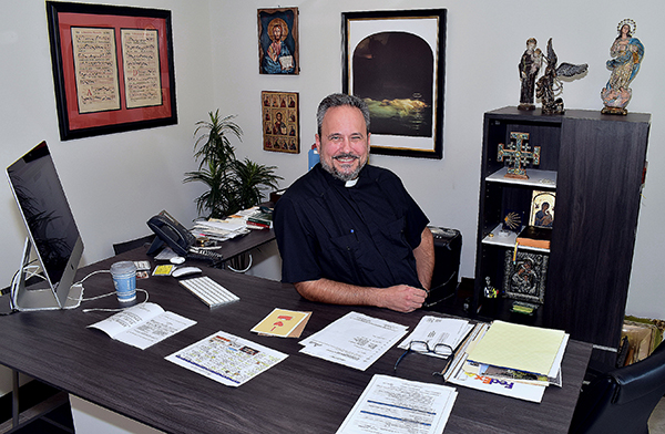 Father David Zirilli shows his new desk, which allows him to sit or stand. The desk is housed in a complex of offices, rectory and a chapel, dedicated this past May 2020.